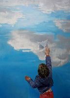 Child holding a paper airplane against a blue sky with clouds
