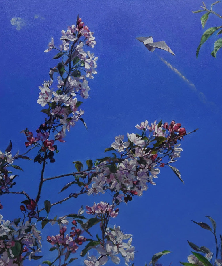 Flowering tree branch with pink and white flowers against a blue sky with a kite flying.