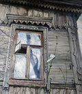 Old wooden house with decorative window frame and weathered exterior