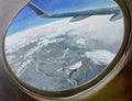 View from an airplane window showing a landscape below with clouds.