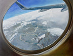 View from an airplane window showing a landscape below with clouds.