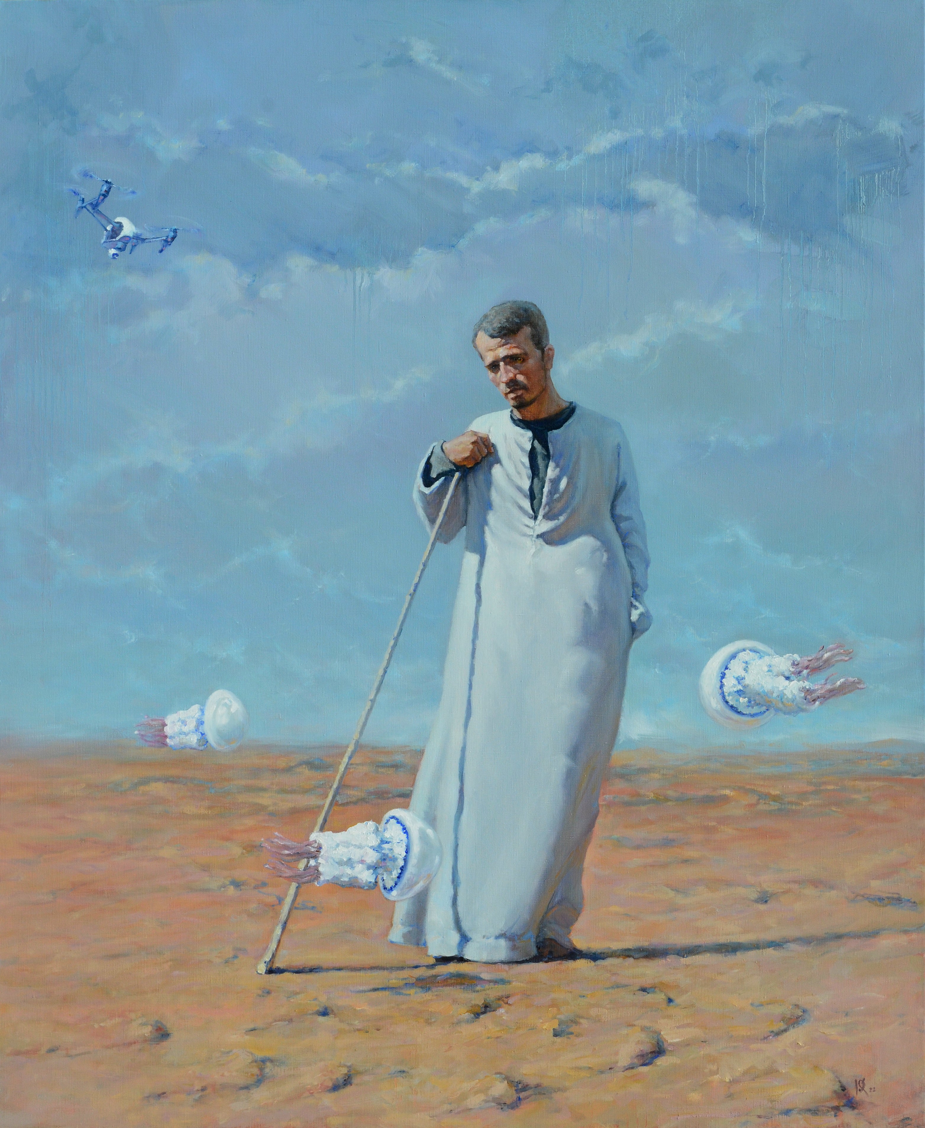 Man in a long white robe standing in a desert with kites flying around him.