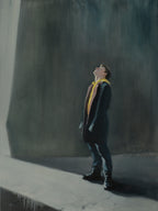 Man in a suit and yellow tie looking up against a dark wall