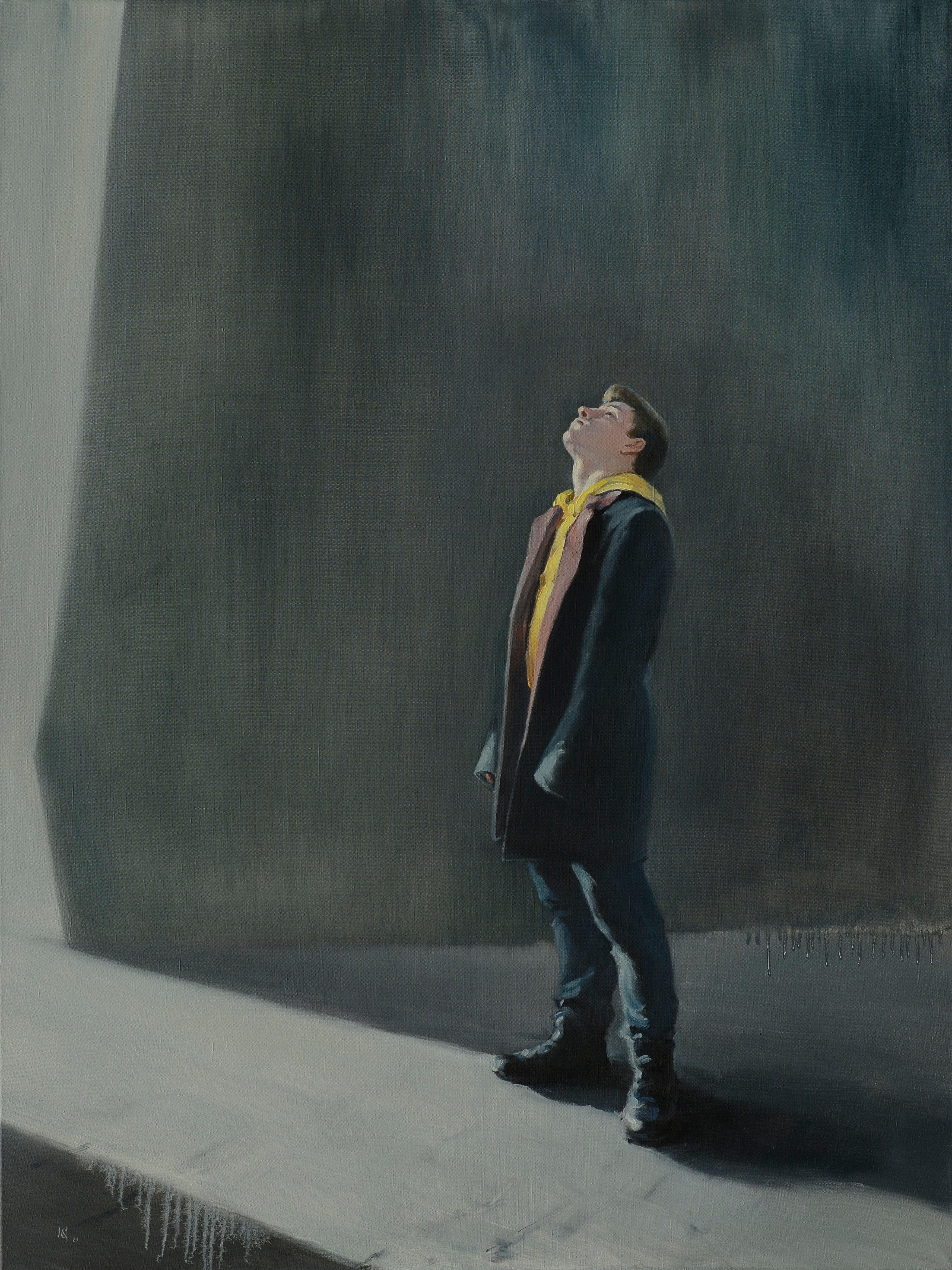 Man in a suit and yellow tie looking up against a dark wall