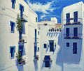 White buildings with blue doors and windows, adorned with flowers, under a blue sky.