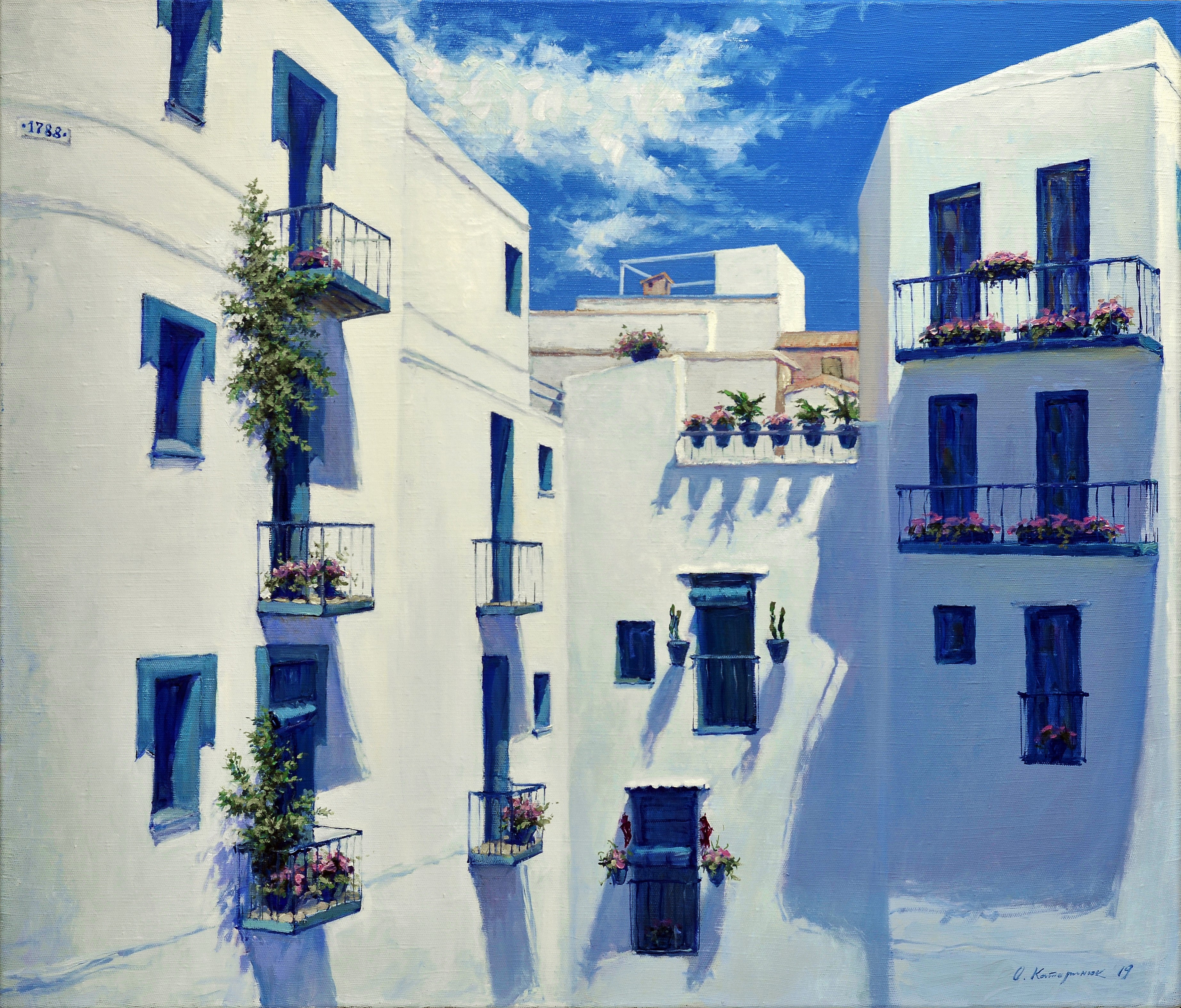 White buildings with blue doors and windows, adorned with flowers, under a blue sky.