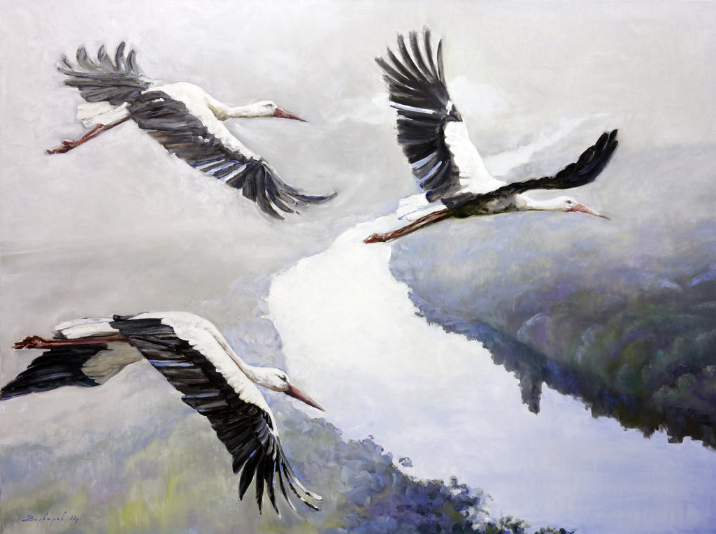 Three storks flying over a reflective water surface with a blurred natural background