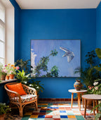 Living room with blue walls, colorful floor, and decorative plants.