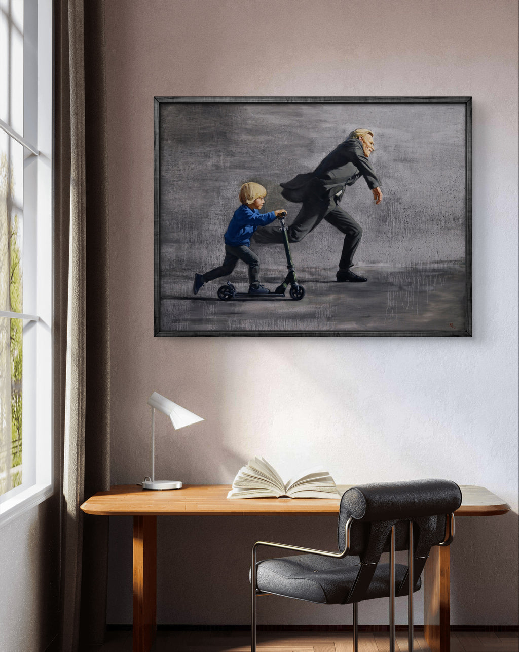 Framed artwork of a man and child on a scooter above a desk with an open book.