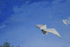 White kite flying against a blue sky with scattered clouds
