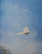 Paper airplane flying against a blue sky with buildings at the bottom