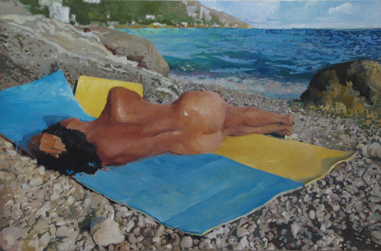 Person lying on a blue and yellow towel by the ocean