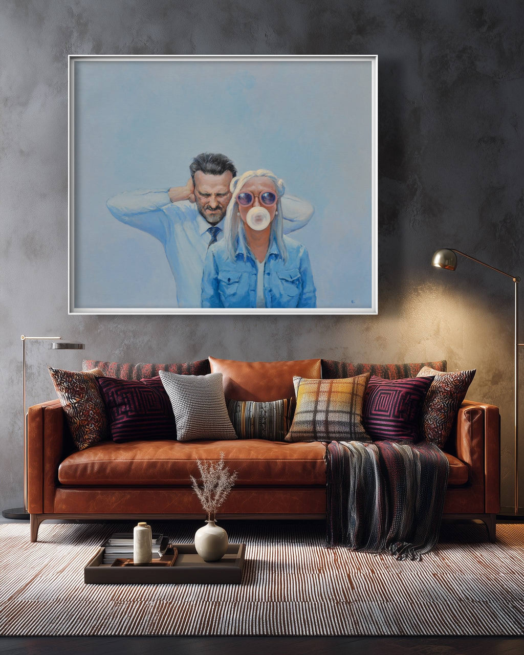 Framed artwork of a couple on a wall above a brown leather sofa with decorative pillows.