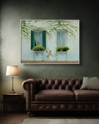 Framed artwork of a window scene with greenery above a brown sofa and lamp.