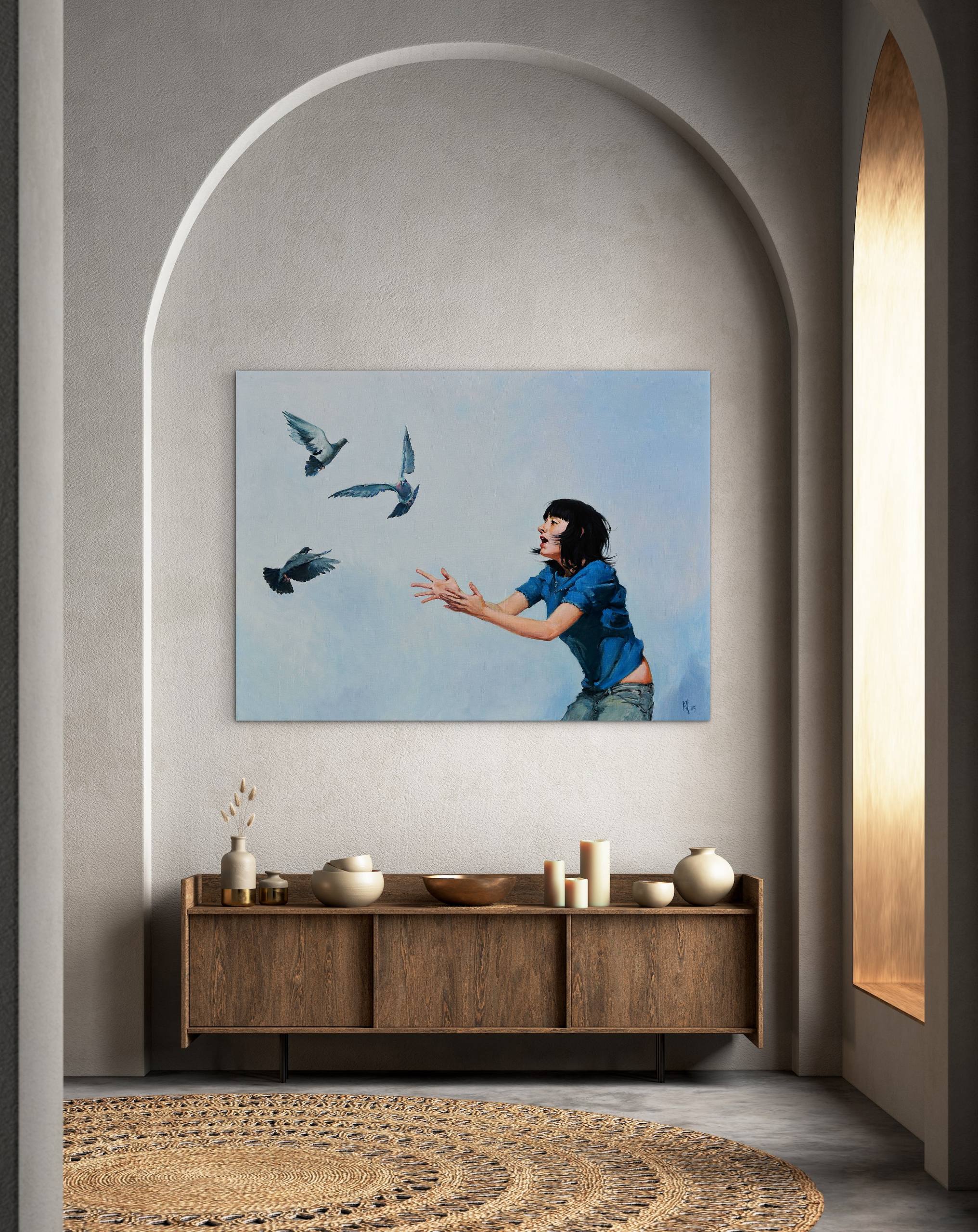 Framed artwork of a woman with birds on a wall above a wooden cabinet.