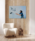 Room interior with a white armchair, wooden side table, and a painting of a woman with birds on the wall.