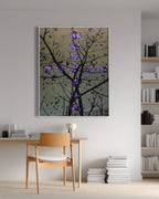 Framed artwork of a tree with purple flowers in a modern room with a chair and books.