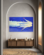 Framed artwork of airplanes in a blue sky with clouds on a wall above a wooden cabinet.