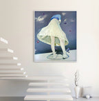 Framed artwork of a person in a white dress with a blue hood on a white wall.