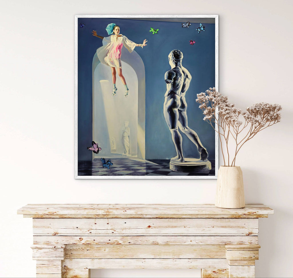 Framed artwork of a woman in a glass dome with a statue on a wooden console table.