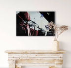 Framed artwork on a wall above a wooden console table with a vase of dried flowers.