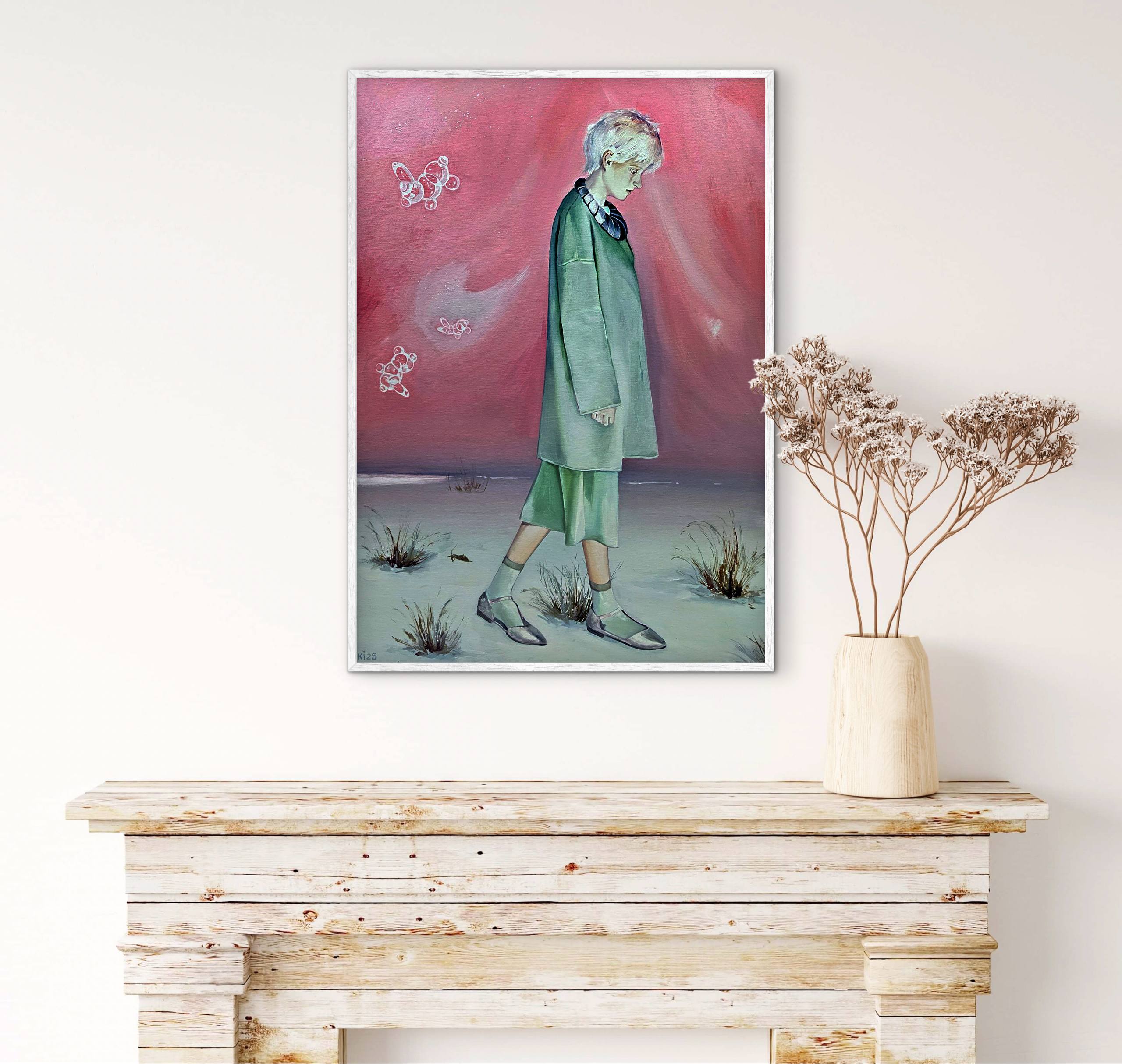 Framed artwork of a person in a green outfit against a pink sky, displayed on a white wall above a wooden console table.