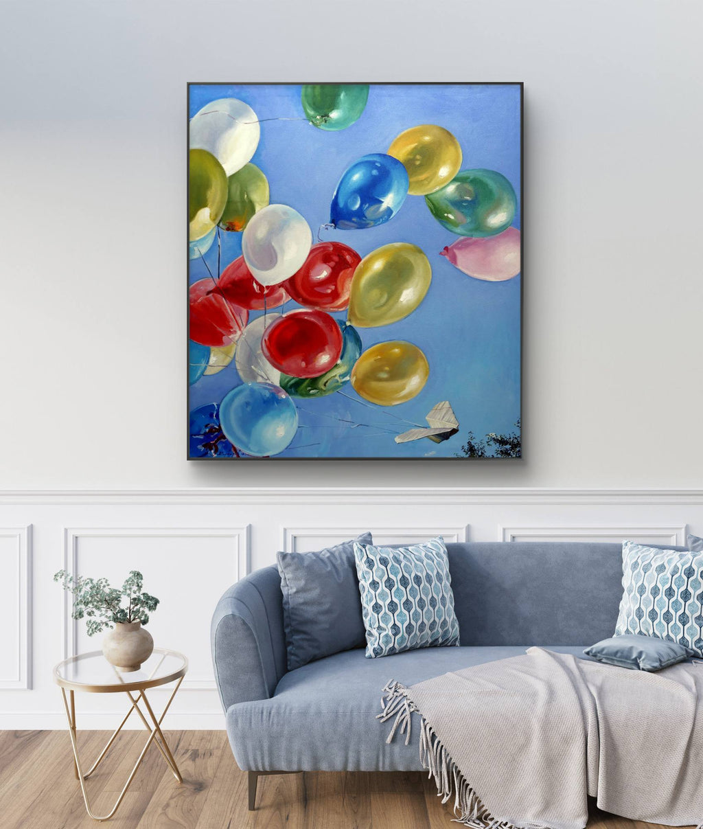 Colorful balloon painting on a wall above a sofa in a living room.
