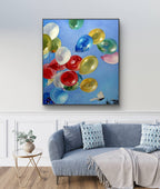 Colorful balloon painting on a wall above a sofa in a living room.