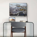 Modern office setup with a glass desk, gray chair, laptop, and framed artwork on a white wall.