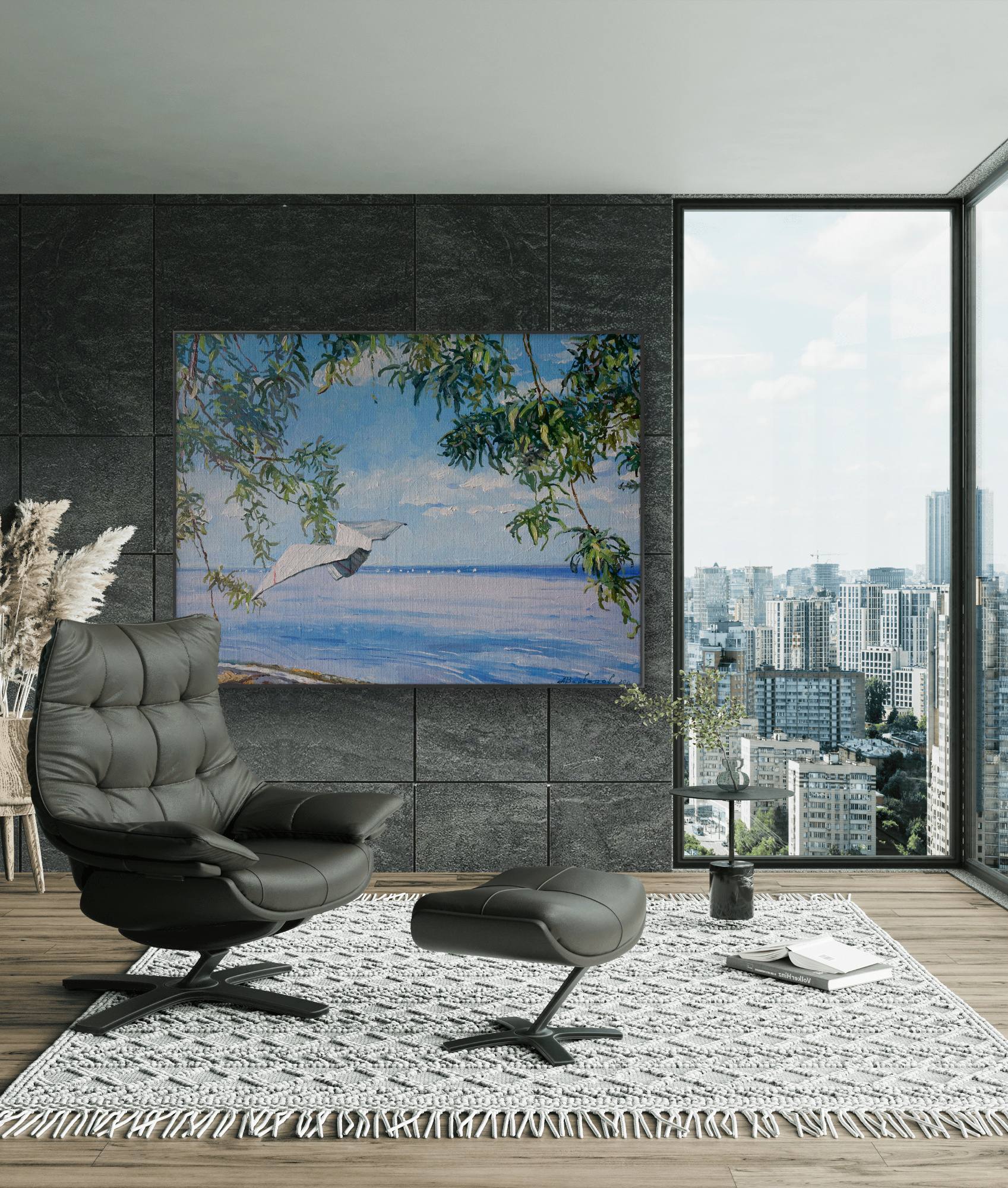 Modern living room with a gray armchair, ottoman, and a large painting of a beach scene.