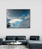 Framed artwork of a cloudy sky above a modern living room with a gray sectional sofa.