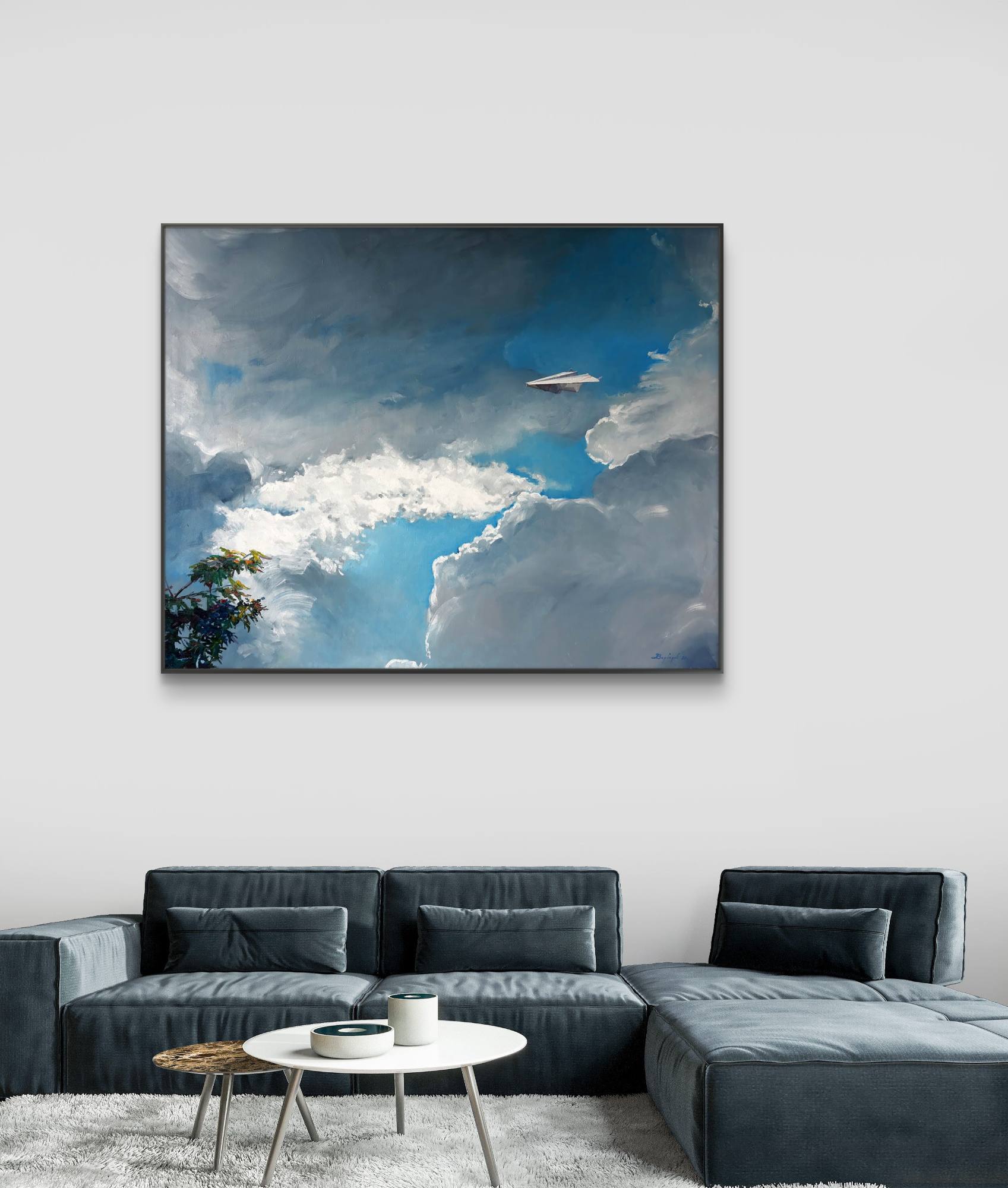 Framed artwork of a cloudy sky above a modern living room with a gray sectional sofa.