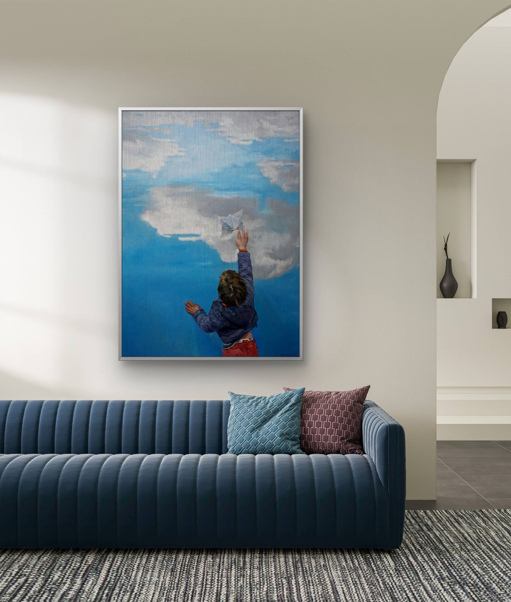 Framed artwork of a person painting a cloud on a blue sky above a modern blue sofa.