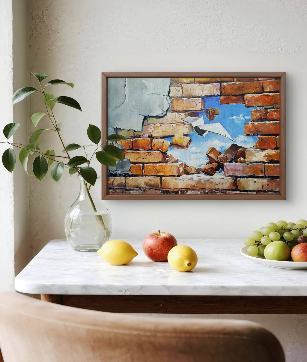 Framed abstract artwork on a wall above a table with fruits and a vase.