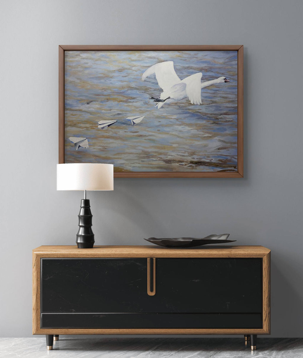 Framed artwork of birds over water above a wooden console table with a lamp and decorative bowl.