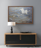 Framed artwork of birds over water above a wooden console table with a lamp and decorative bowl.