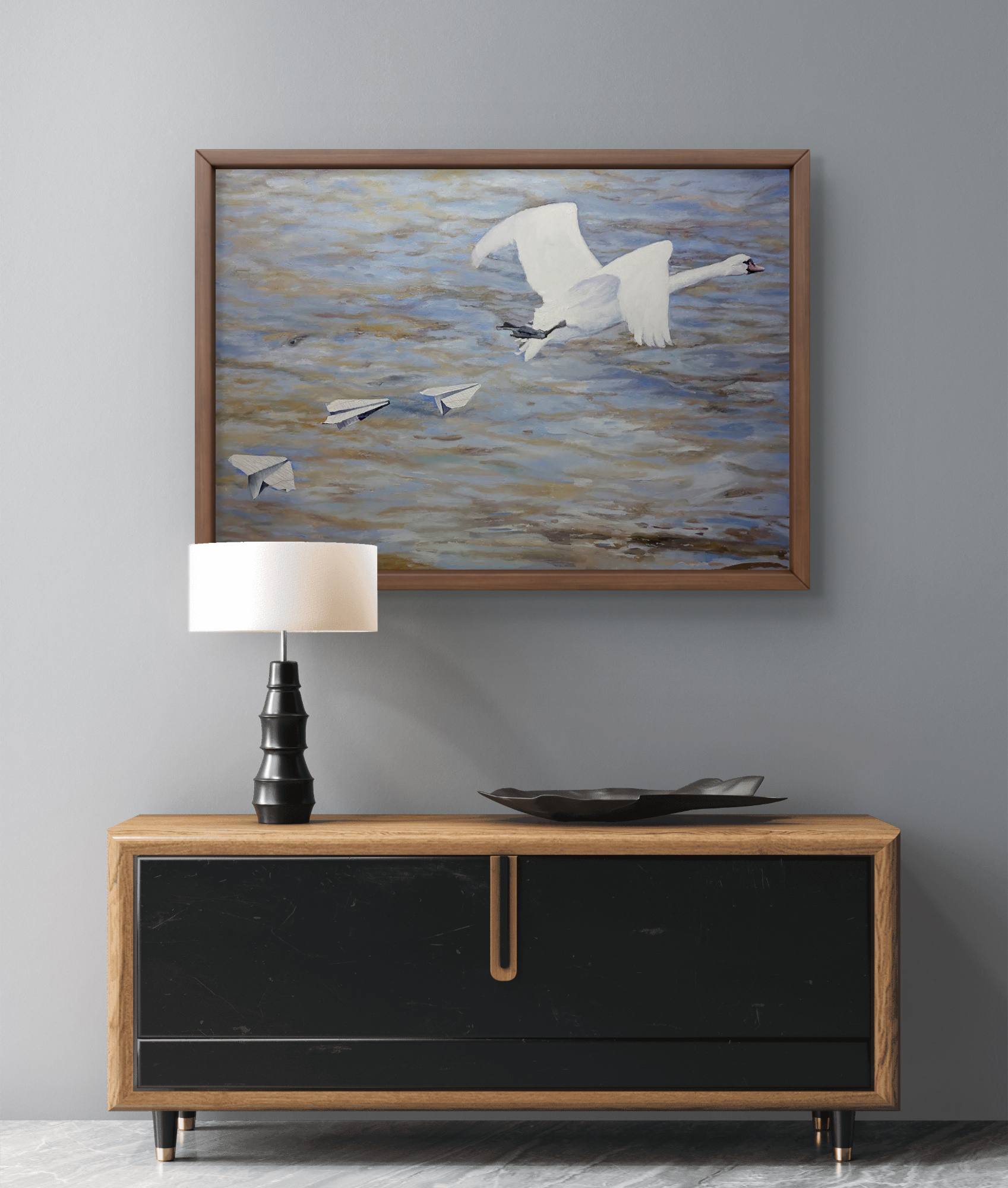 Framed artwork of birds over water above a wooden console table with a lamp and decorative bowl.