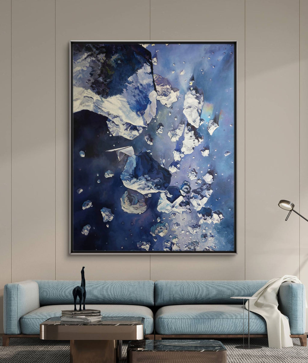 Abstract blue and white painting on a wall above a blue sofa.