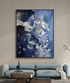 Abstract blue and white painting on a wall above a blue sofa.