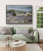 Living room with a green sofa, round wooden coffee table, and a large framed painting of a landscape.