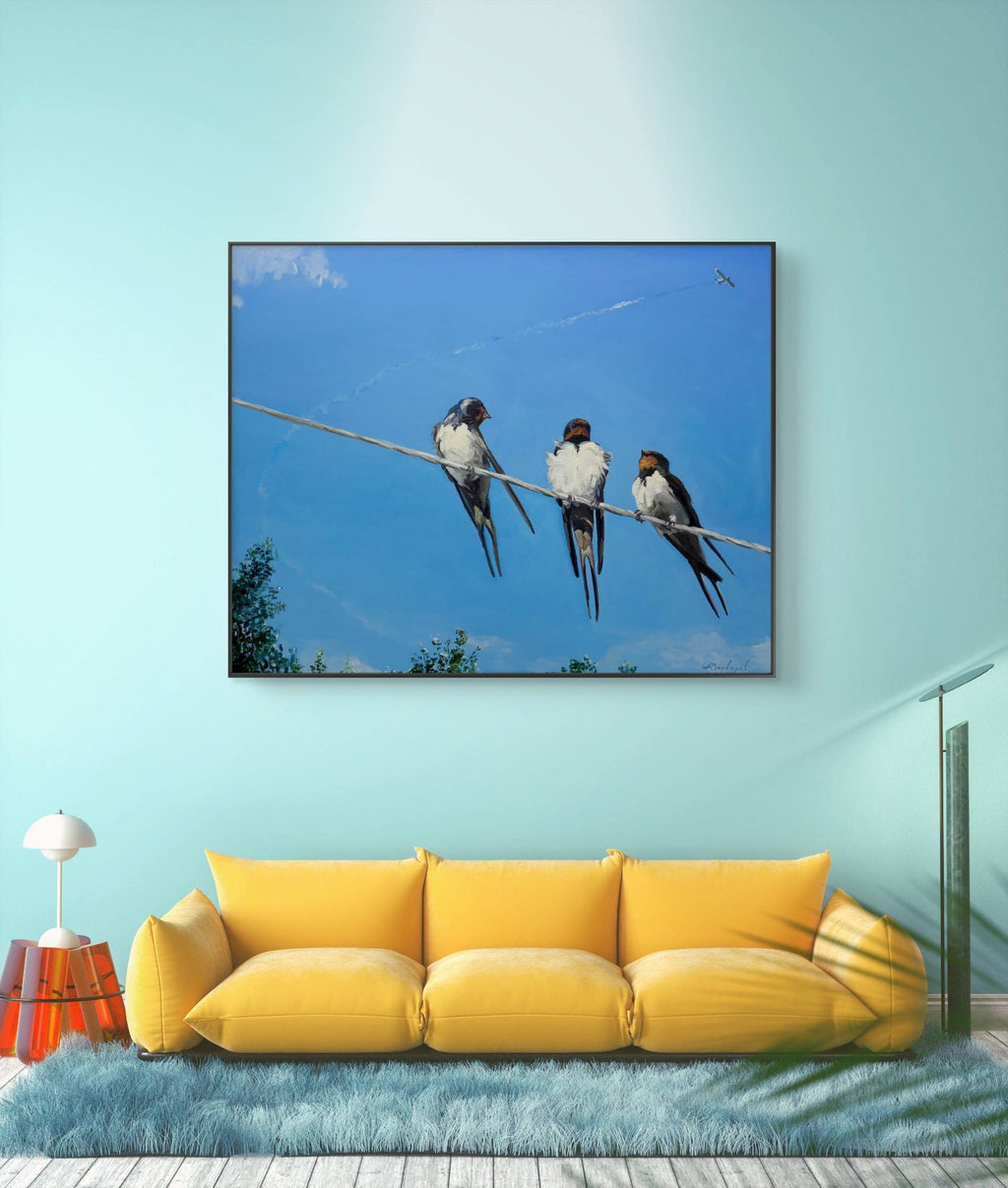 Framed artwork of birds on a wire above a yellow sofa in a room with light blue walls.