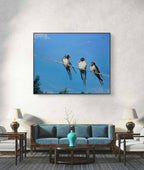 Framed artwork of birds on a wire above a living room setting.