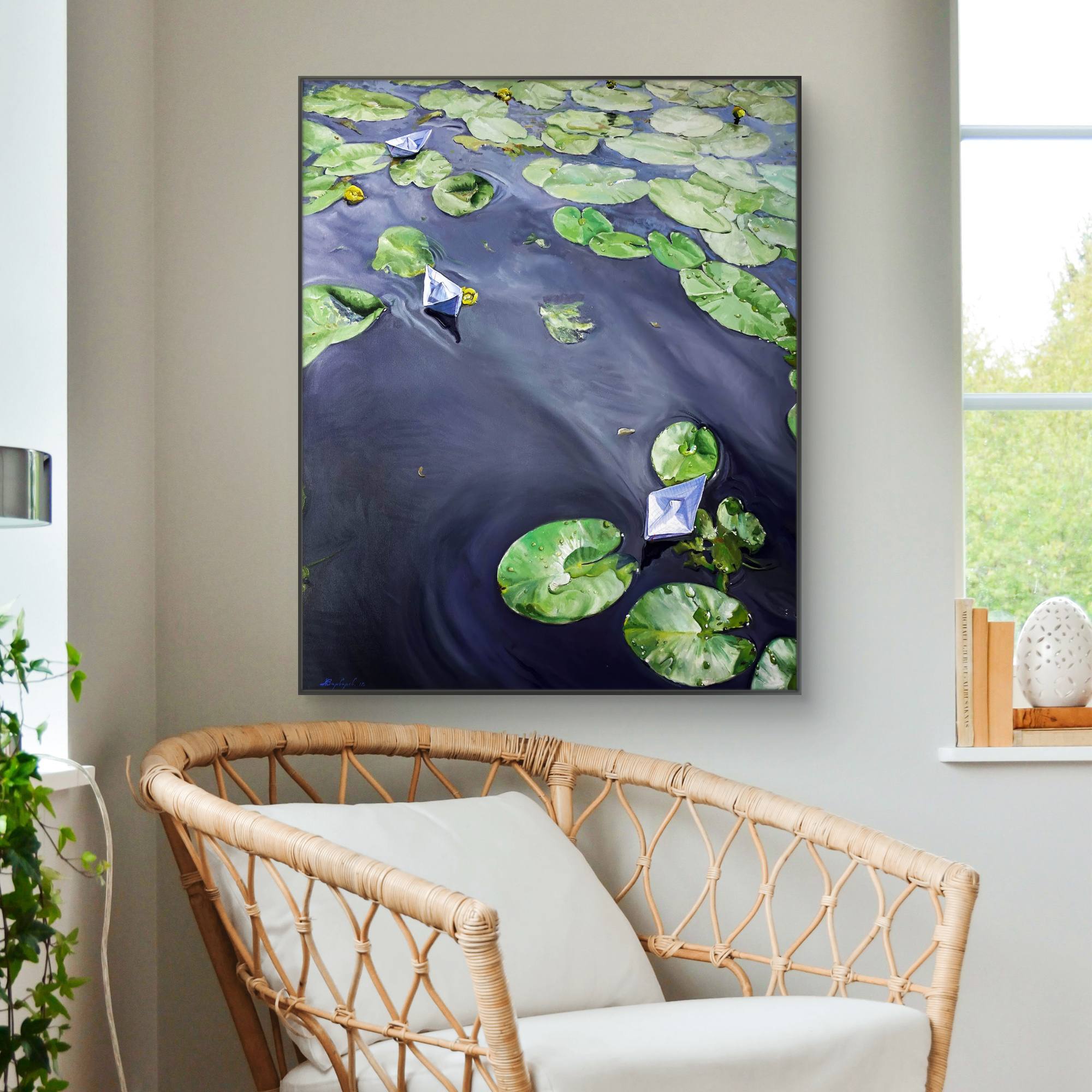 Framed artwork of water lilies on a wall above a wicker chair.