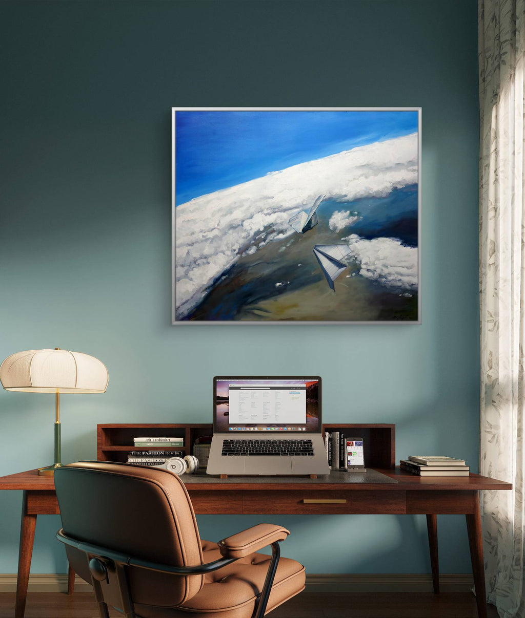 Home office with a desk, chair, laptop, and framed artwork on a blue wall.