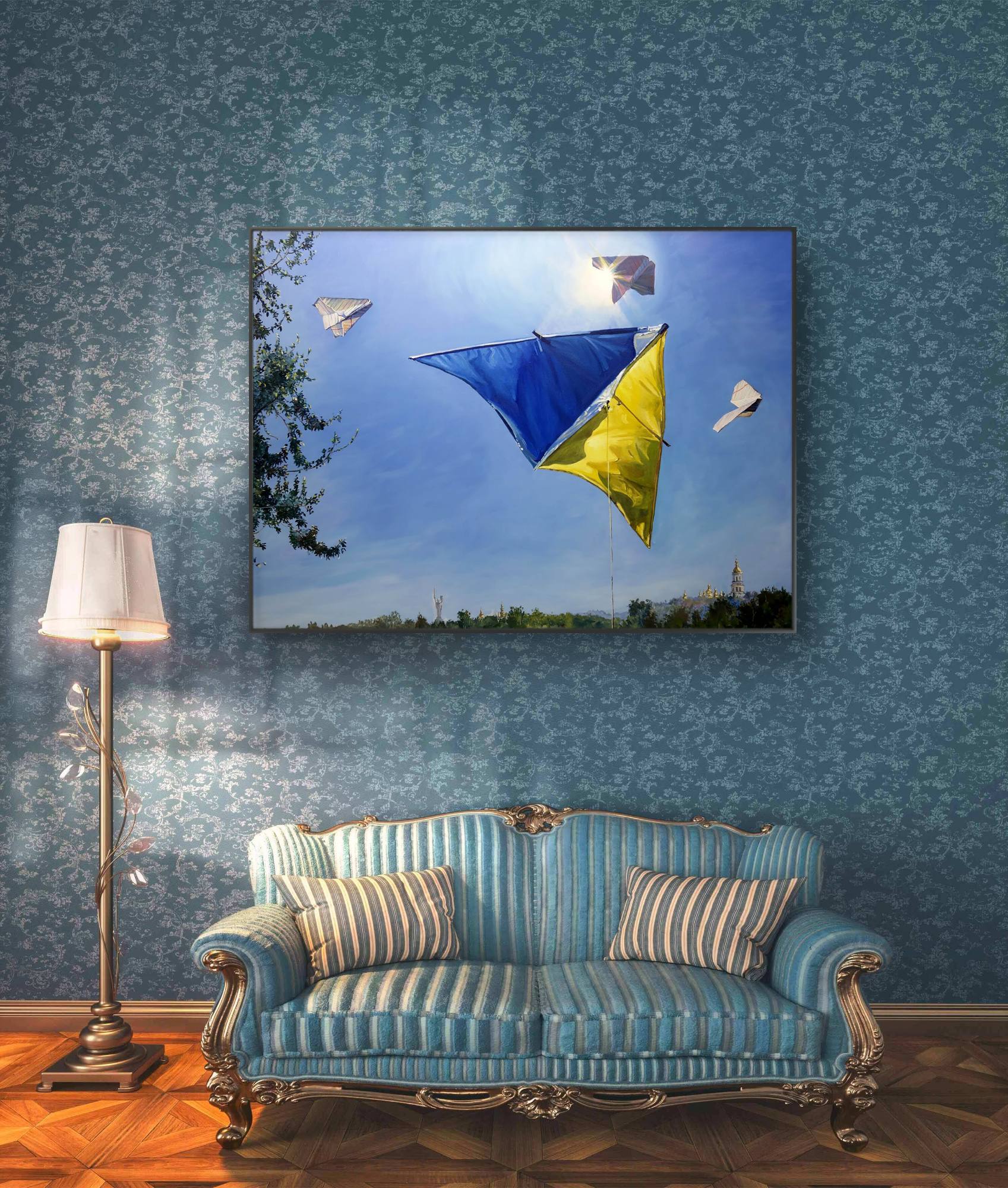 Living room with a blue sofa, lamp, and wall art of kites.