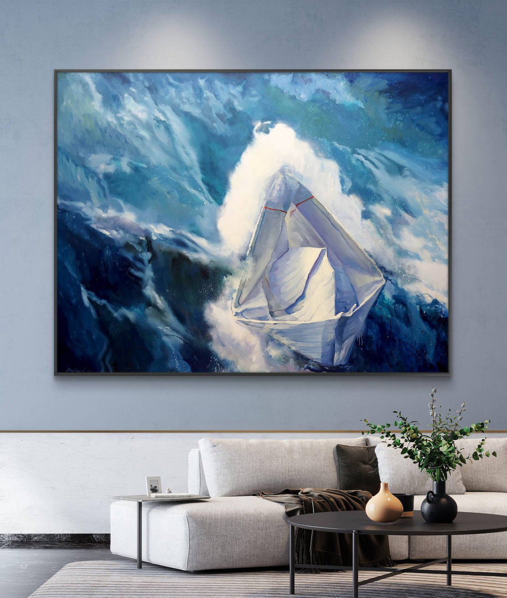 Framed painting of a sailboat in the mountains on a wall above a sofa.