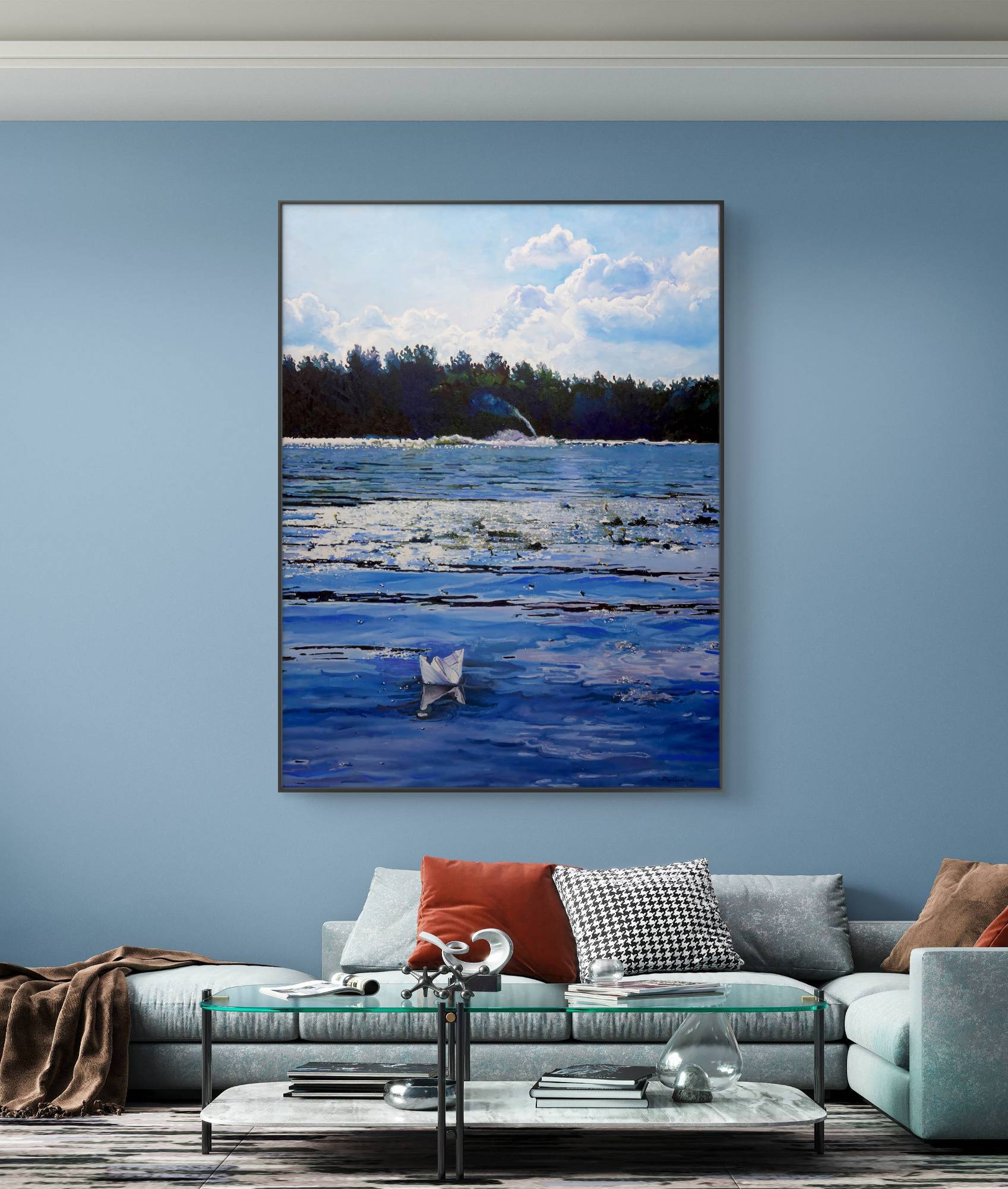 Framed artwork of a coastal scene hanging on a blue wall above a sofa.