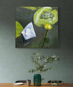 Framed painting of a frog on a lily pad above a table with decor items.