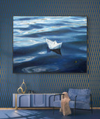 Framed artwork of a paper boat on water in a room with blue walls and furniture.