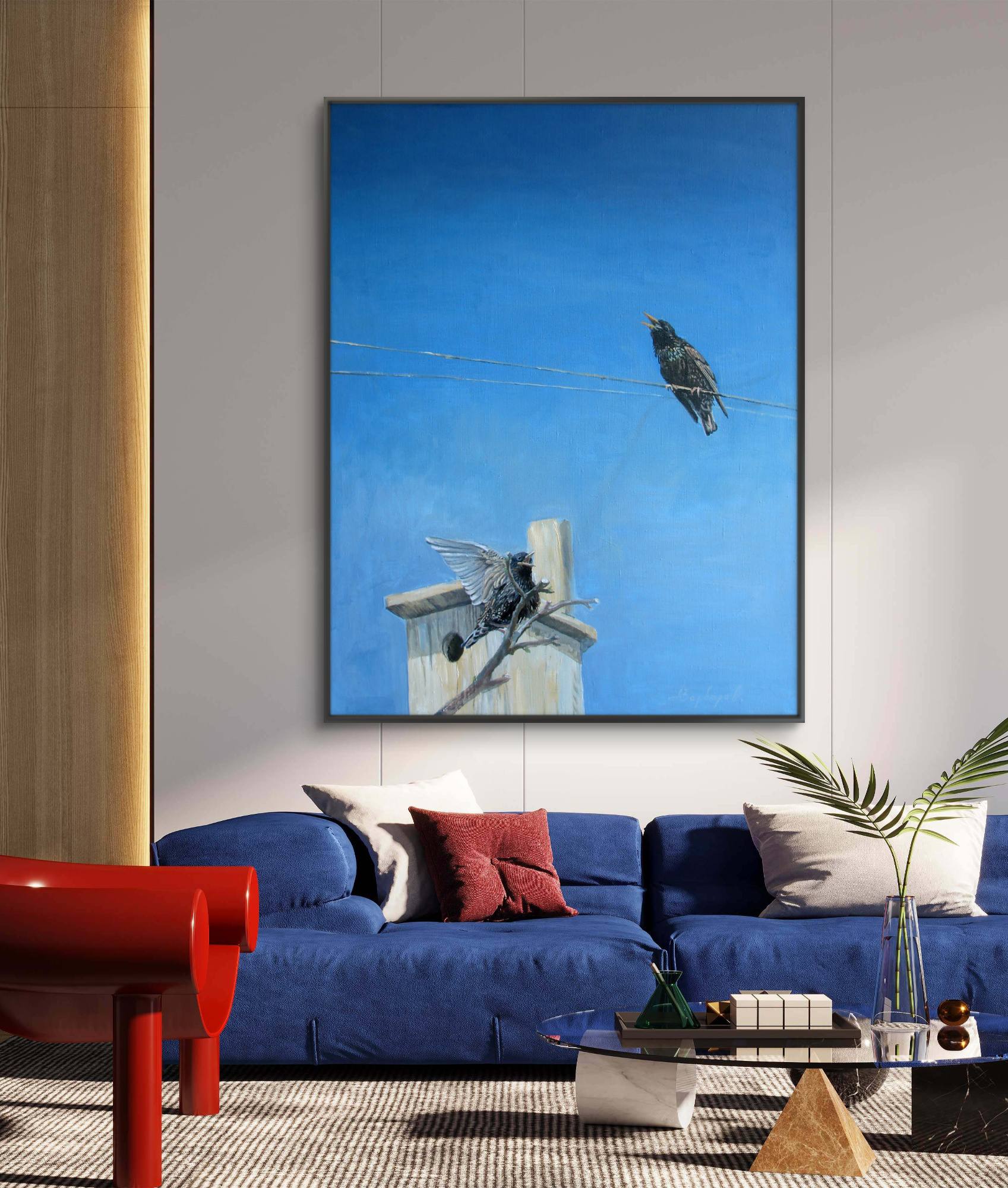 Framed artwork of a bird on a wire above a blue sofa in a living room.
